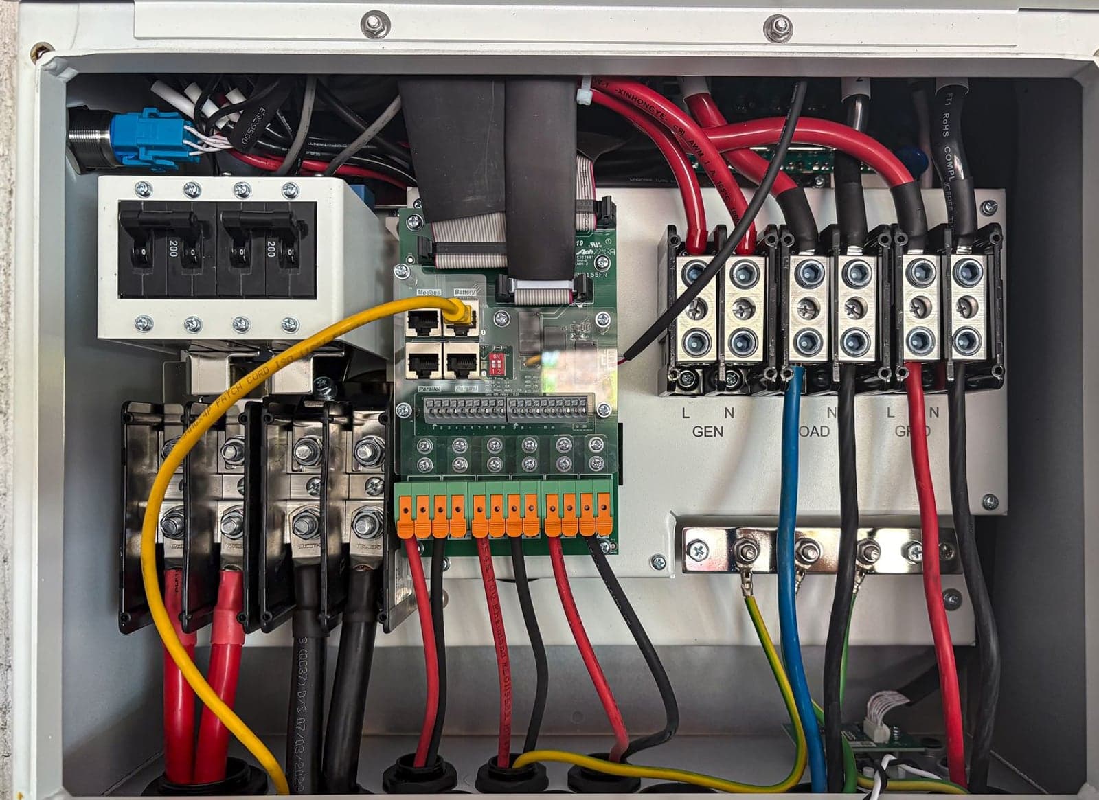 The inside of an electrical control panel, showing terminals, a control board and coloured wiring.